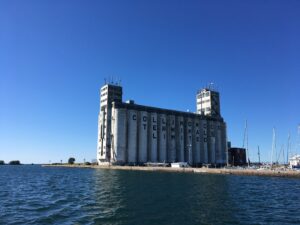 Industrial concrete silo/terminal by the water with antennas on top and the words Collingwood Terminals Limited visible against a clear blue sky.